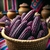 Sementes de milho roxo peruano em uma cesta de vime, com fundo decorado e potes ao redor.