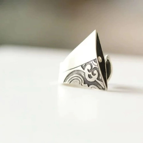 Anel de prata com design detalhado, apresentando formas curvas e uma ponta afilada.