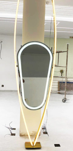 Espelho gota com arco dourado iluminado em um ambiente interno, destacando seu design moderno e elegante.