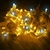 Fios de pisca pisca com 100 LEDs em cores amarelas e brancas, enrolados em um fundo escuro.