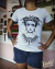 Blusinha branca com ilustração estilo old school de Frida Kahlo com olhos brancos, coroa de folhas com caveira e colar de teia de aranha.