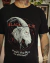 Camiseta preta com ilustração do bode Black Phillip com olhos vermelhos e a frase “Wouldst thou like to live deliciously?”, referência ao filme A Bruxa.