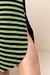 Detalhe do vestido visco listrado, exibindo listras em verde e azul marinho com um botão na lateral.