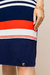 Detalhe do vestido visco crepe listrado, destacando as listras vermelha, branca e azul, com a etiqueta da marca visível na parte inferior.
