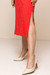 Detalhe do vestido canelado vermelho com fenda lateral, combinado com sapatos de salto bege.