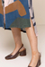 Detalhe do vestido chemise Wave estampado, com estampa colorida e fenda lateral, combinado com sapatos de salto marrom.