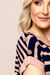 Zoom de uma blusa feminina de visco listrada, com detalhes em botões decorativos nos ombros.
