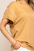 Detalhe de uma Blusa Visco Crepe na cor bege, com mangas curtas e detalhe em viés branco.