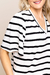 Detalhe de uma blusa de crepe linho listrada em preto e branco com mangas curtas e decote em V.