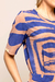 Detalhe da Blusa Wave Estampada com design em azul e tons terrosos, destacando as mangas curtas.