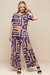 Modelo vestindo uma blusa estampada em tons de azul e bege, com mangas curtas e calça combinando.