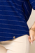 Detalhe da blusa visco crepe listrada na cor azul marinho, com listras bege e etiqueta dourada na parte inferior.