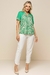 Modelo usando uma blusa visco crepe estampada em verde com design de folhas, combinada com calças claras.