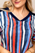 Blusa visco crepe estampada com listras em azul, vermelho e branco, destacando o decote em V e detalhes de manga curta.