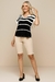 Modelo usando blusa visco crepe listrada preta e branca, com manga curta e calça bermuda bege, coleção de verão 25