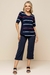 Modelo usando blusa de visco com listras em azul marinho, branco e vermelho, combinada com calças escuras.