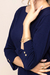 Detalhe da blusa visco azul escura com mangas 3/4 com punhos e botões dourados.