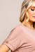 Detalhe de uma blusa de visco feminina na cor bege com detalhe em botão  dourado na manga curta.