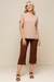 Modelo usando blusa de viscose bege, com mangas curtas, combinada com calça marrom e sandálias.