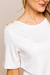 Detalhe da blusa de crepe linho branca com detalhes em botões dourados nos ombros.