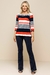 Modelo vestindo blusa visco crepe listrada em cores azul, vermelho e branco, com mangas 3/4 e detalhes em botões, combinada com calça flare azul marinho