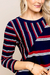 Detalhe da blusa visco crepe listrada com mangas 3/4, apresentando combinação de listras em vermelho, branco e azul.