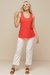 Modelo usando uma regata canelada coral, combinada com calças claras de linho, em um look casual e moderno de verão.