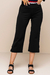 Calças Capri Bodycon na cor preto, com detalhes na barra e usadas com sandálias de salto.