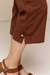 Pernas de uma calça Capri Bodycon marrom, destacando detalhes do acabamento e um botão na barra.