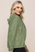 Jaqueta corta vento com capuz na cor verde militar, destacando seu design leve e prático, com bolsos e elástico na cintura.