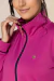 Destaque de um conjunto térmico rosa com zíper e detalhes em azul, com uma pequena logo dourada visível.