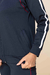 Detalhe do conjunto Thermo com calça tradicional, destacando a jaqueta azul escura com detalhes em vermelho e branco.