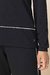 Detalhe do conjunto moletinho com pantalona, destacando a parte inferior da blusa e a calça preta com detalhes em branco.