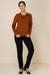Mulher usando um conjunto tricot listrado com calça tradicional, apresentando uma blusa ferrugem com listras pretas e calça preta.