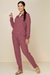 Modelo vestindo conjunto moletinho fleece na cor rosê, composto por jaqueta com zíper e calça jogger, em fundo neutro.
