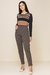 Modelo usando uma calça jogger jacquard em tom escuro, com uma blusa de manga longa listrada em cores terrosas. Look inverno 2025.