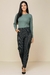 Modelo vestindo calça jogger jacquard cinza e blusa verde, look casual de inverno.