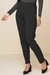 Calça jogger jacquard preta, com detalhes texturizados, modelagem ajustada e bolsos laterais, usada por uma modelo com sapatos de salto preto.