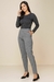 Modelo usando calça jogger jacquard cinza, com blusa de manga longa preta e sapatos de salto. Look inverno 2025 