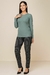 Modelo usando blusa térmica canelada de manga longa na cor verde, combinada com calça escura e sapatos de salto.
