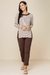 Modelo usando blusa tricot listrada com mangas longas e detalhes em botões, combinada com calça marrom.