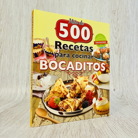 Libro titulado "Más de 500 recetas para cocinar bocaditos" con una variedad de bocaditos en una bandeja.