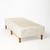 Base sommier Naturalfoam con patas de madera y tapizado en tela clara con logo Naturalfoam