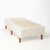 Base sommier Naturalfoam con patas de madera y tapizado en tela clara con logo Naturalfoam