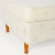 Detalle de esquina de base sommier con tapizado claro y patas de madera y esquinero blanco de Naturalfoam