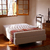 Base sommier Naturalfoam en una habitación iluminada, con ventana y mobiliario de madera.