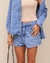Camisa feminina jeans azul clara Duomo, com fechamento por botões e bolsos frontais no peito.


