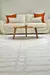 Tapete Roma Off White 2,40x3,00M com padrão geométrico em sala de estar com sofá branco e almofadas marrons