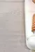 Tapete sisal cinza claro modelo Ravena 2,00x2,50 colocado ao lado de sofá branco com almofada laranja