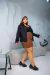 Modelo usando uma jaqueta plus size preta, saias xadrez e sapatos pretos em um ambiente moderno.